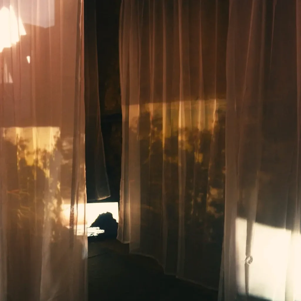 Golden light installation with translucent hanging fabric panels and soft organic shadow projections in an immersive interior space.